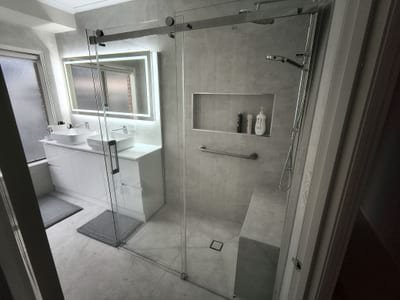 Newly renovated bathroom showing fluted vanity panels, stone benchtop and tiled shower